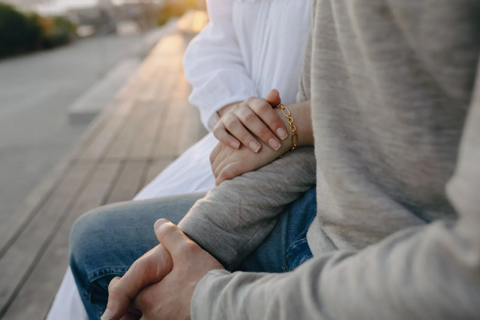 Two people holding hands on a park bench