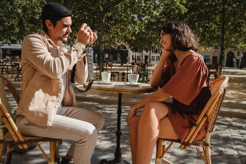 Two people meeting at an outdoor café table on a sunny day