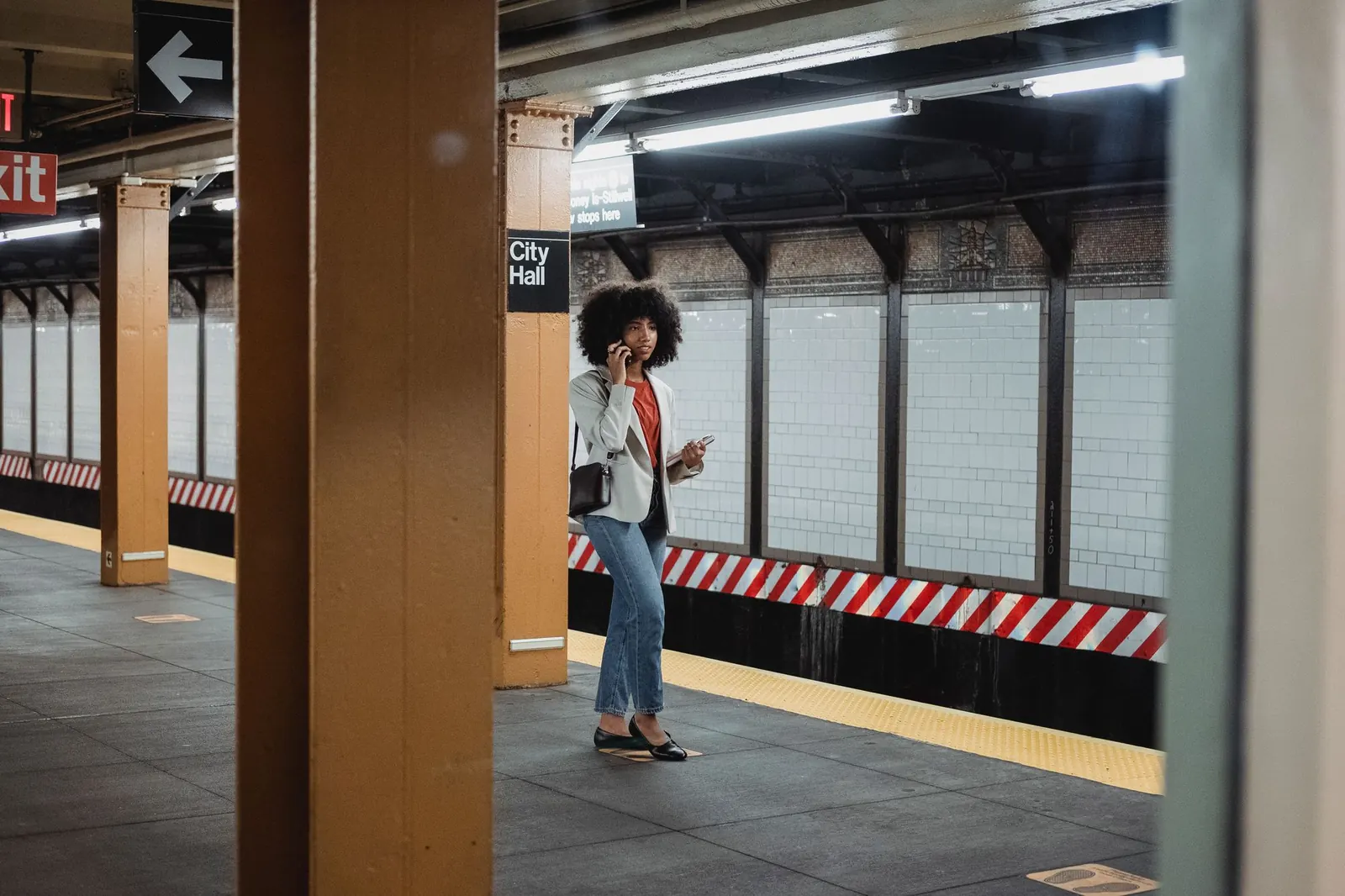 A woman with her phone on a New York City subway platform