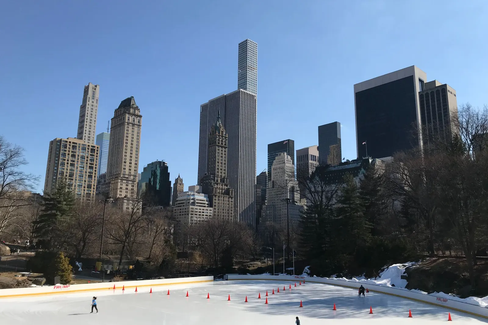 Ice skaters on the Central Park rink with the Midtown skyline behind