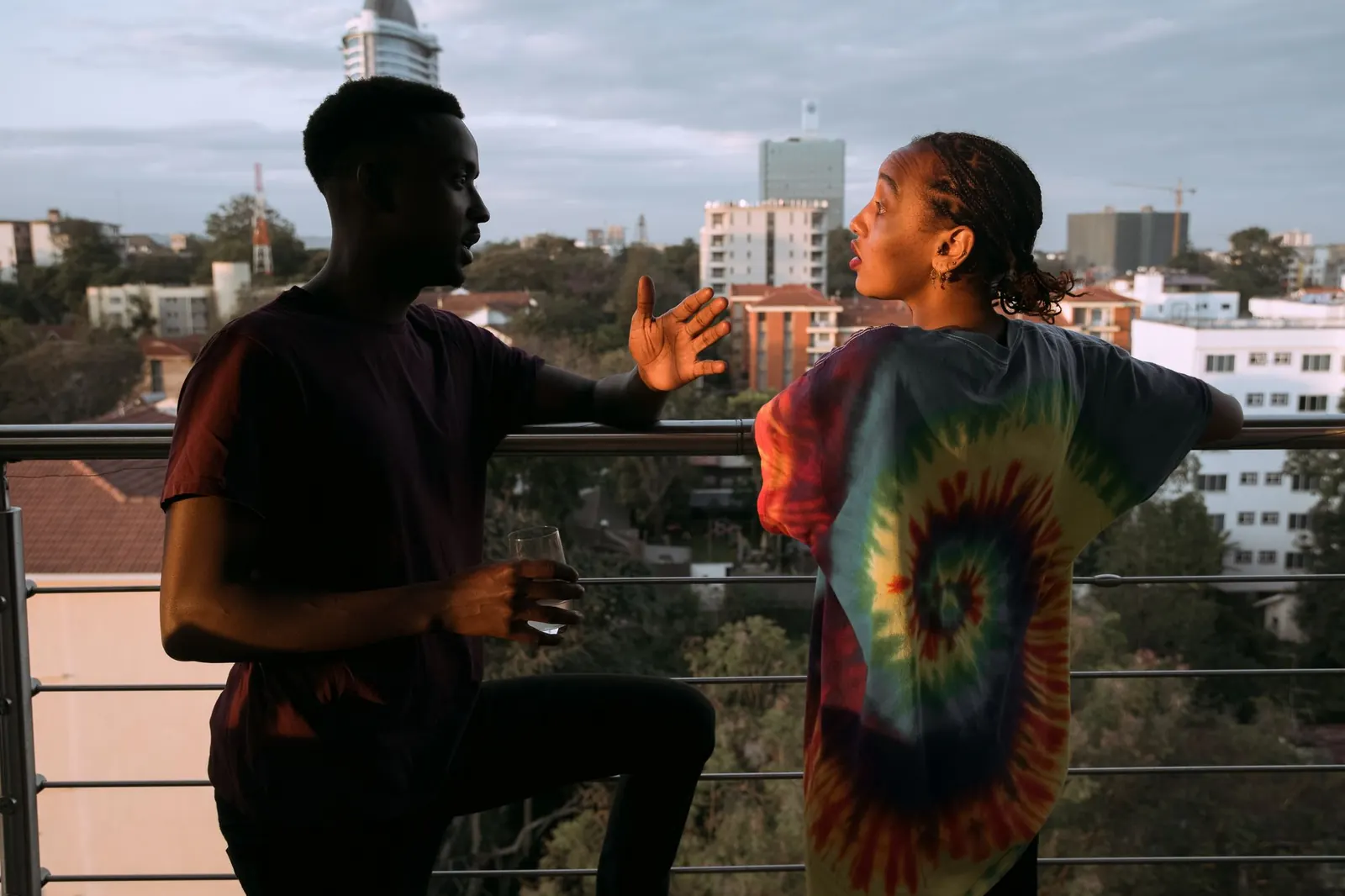 Two people talking on a city balcony at sunset