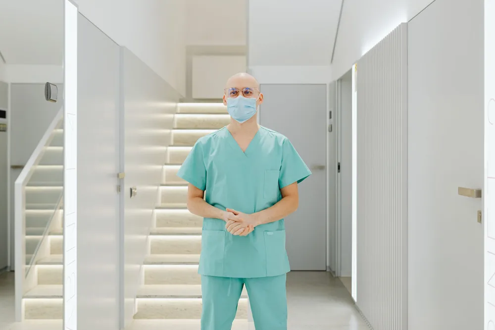A healthcare worker in scrubs in a clinic hallway