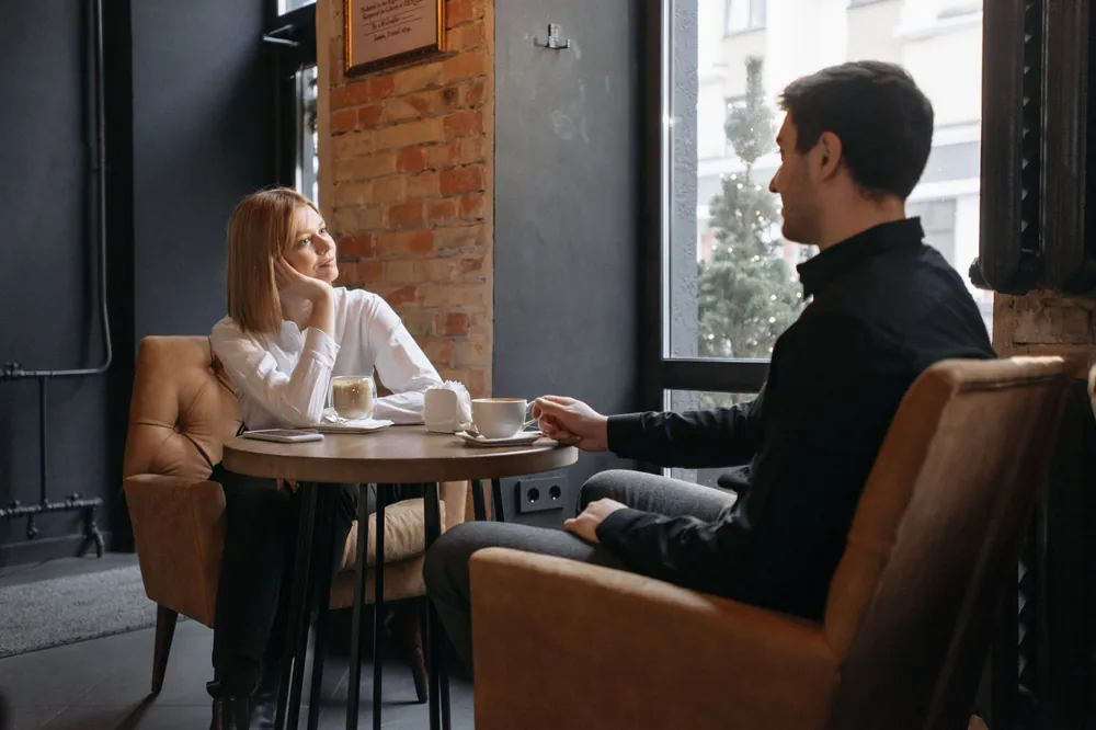 A couple talking over coffee by a café window
