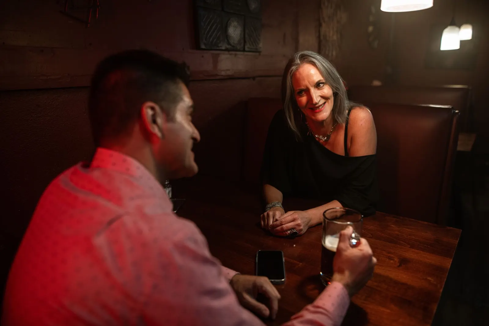 A man and a woman talking over drinks in a cozy bar