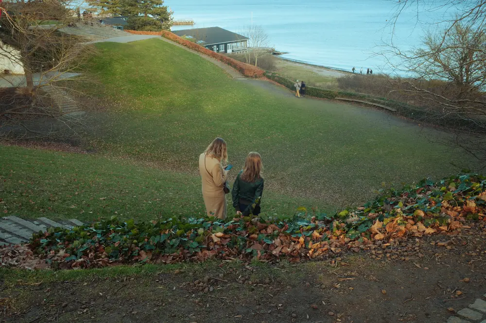 Two women walking together through a waterside park