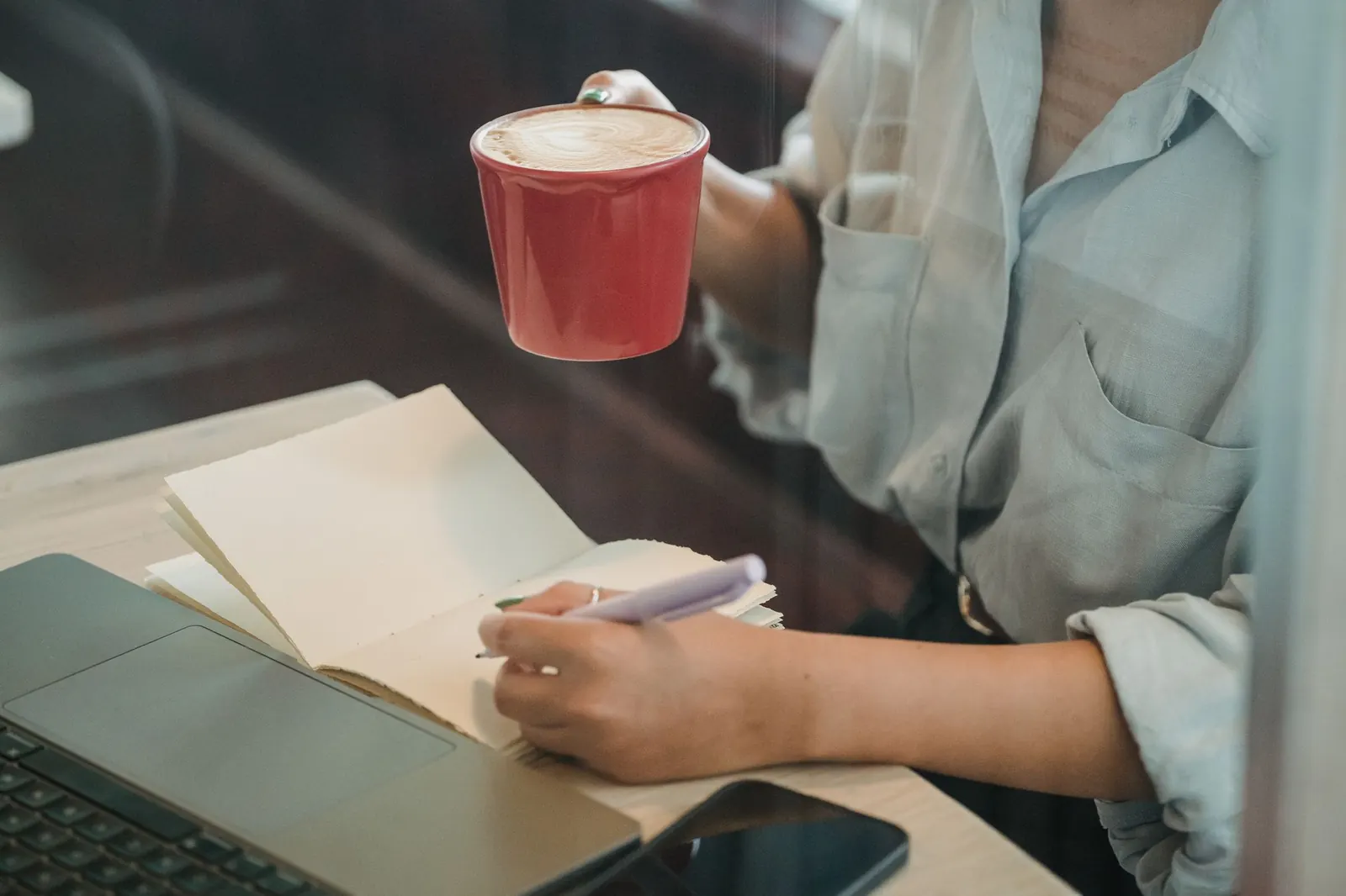 A woman writing in a notebook over coffee in a café