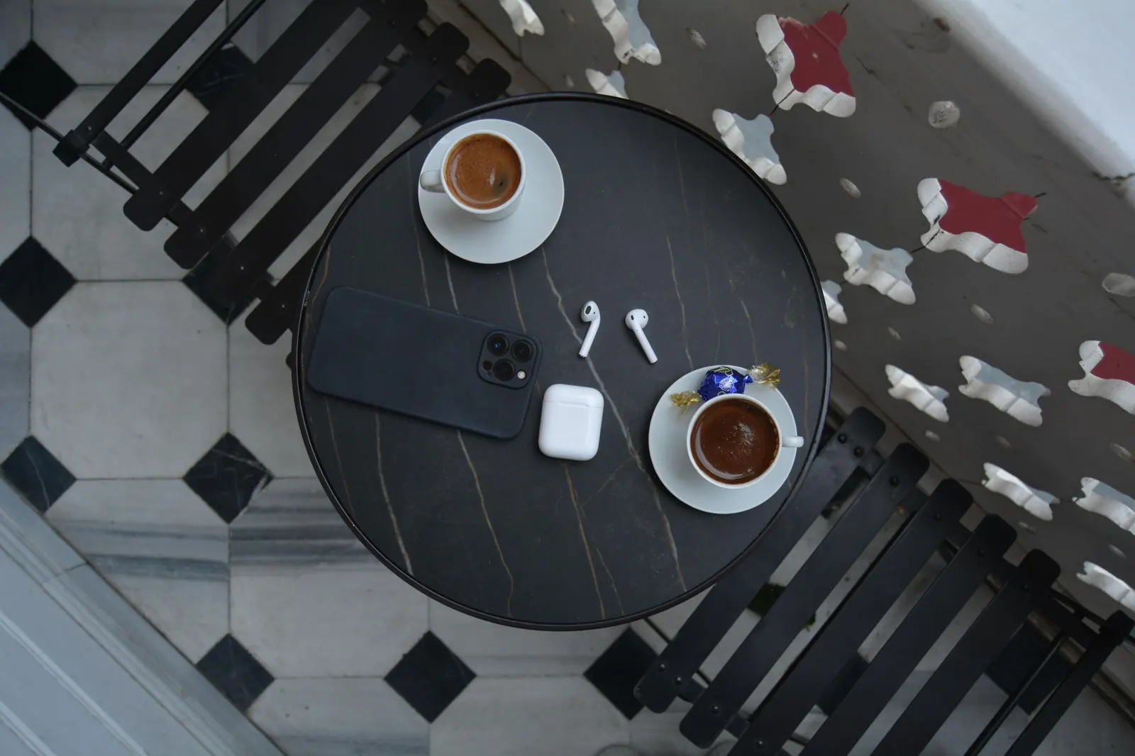A phone, earbuds and coffee on a café table