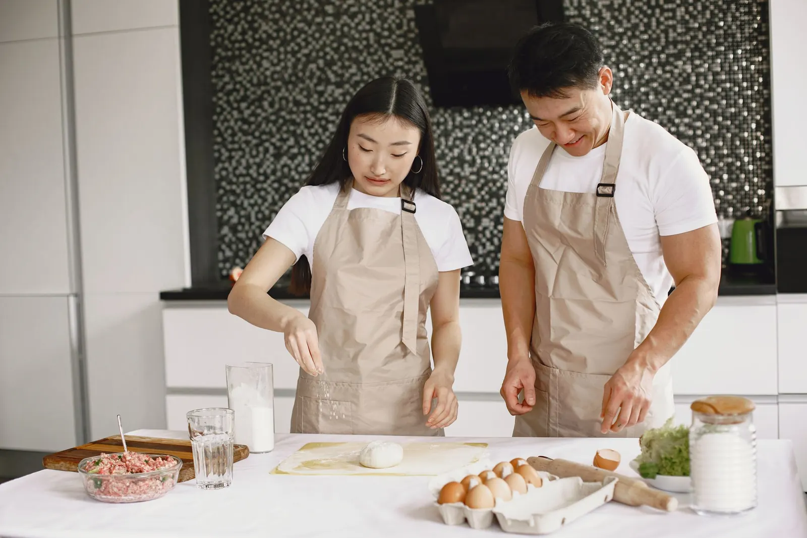A couple in aprons cooking together in a modern kitchen