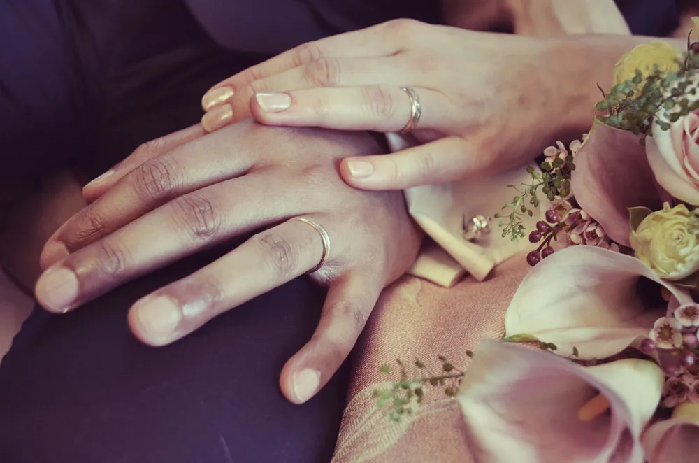 A couple's hands with wedding rings among flowers