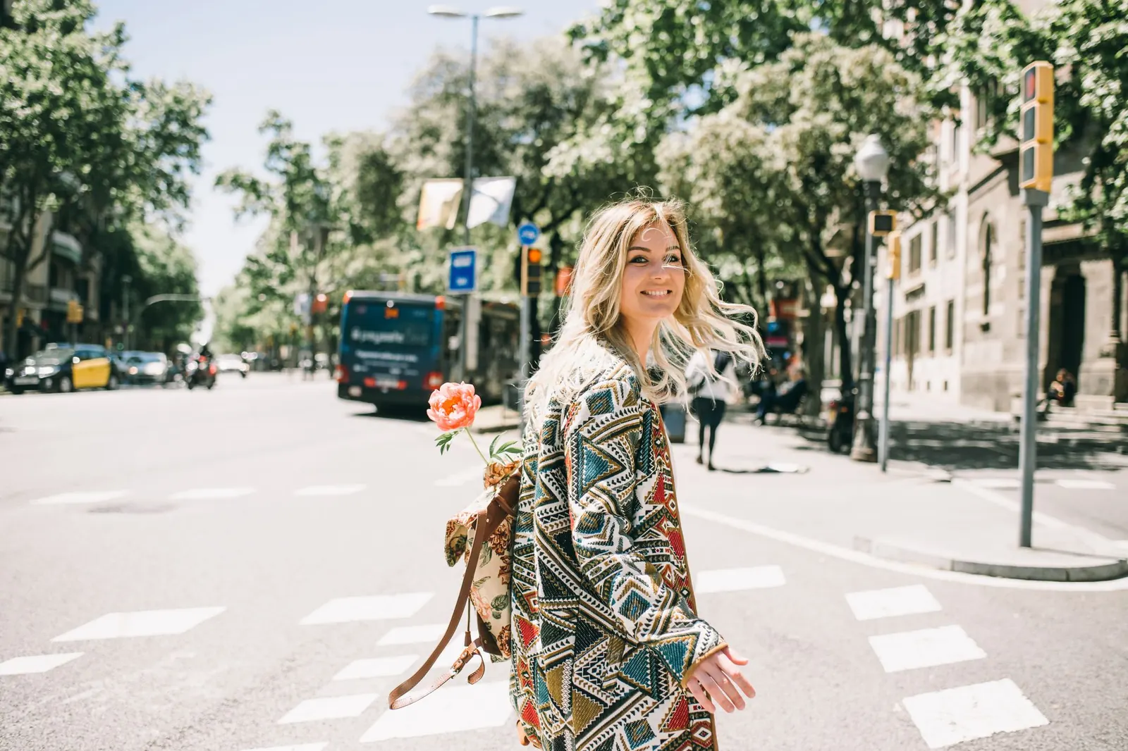 A smiling woman crossing a sunny city street