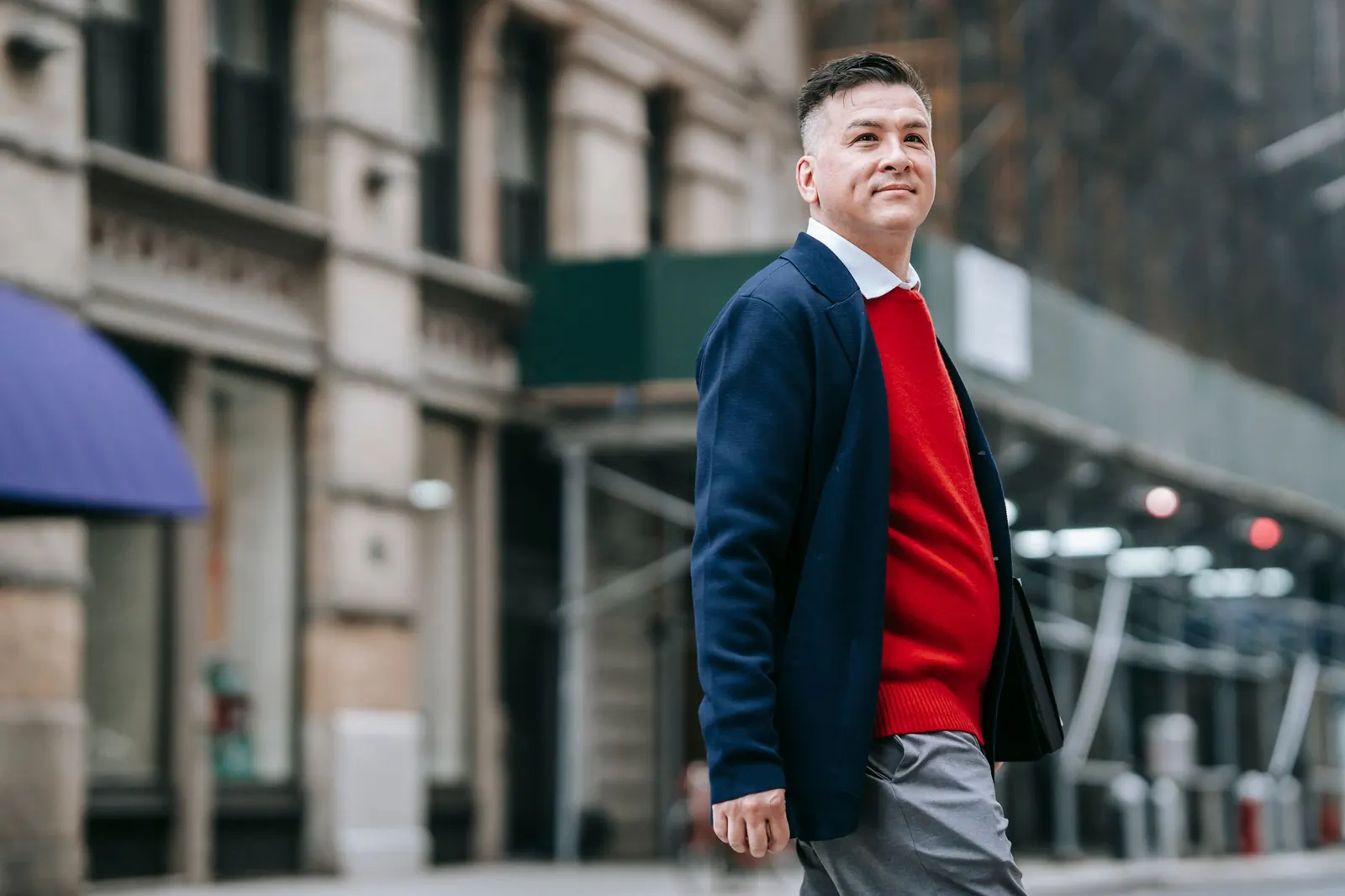 A man in a red sweater and blazer walking downtown