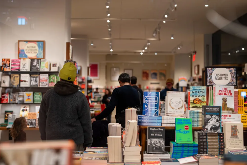 People browsing shelves in a warmly lit New York bookstore
