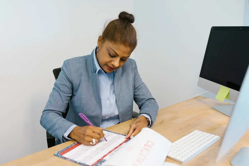 A businesswoman writing plans in her desk calendar