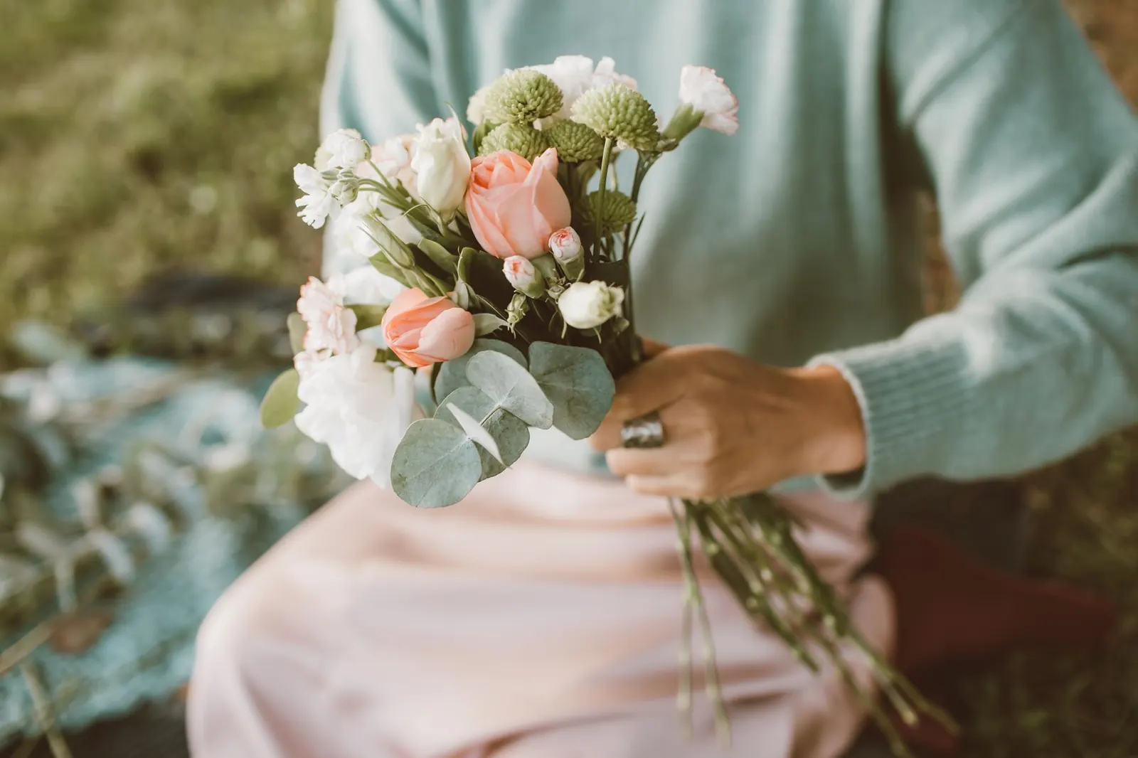 A hand holding a small pastel bouquet of flowers