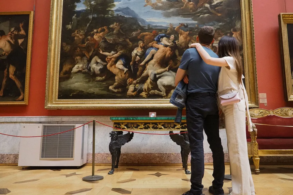 Two people looking at a large painting in a museum gallery