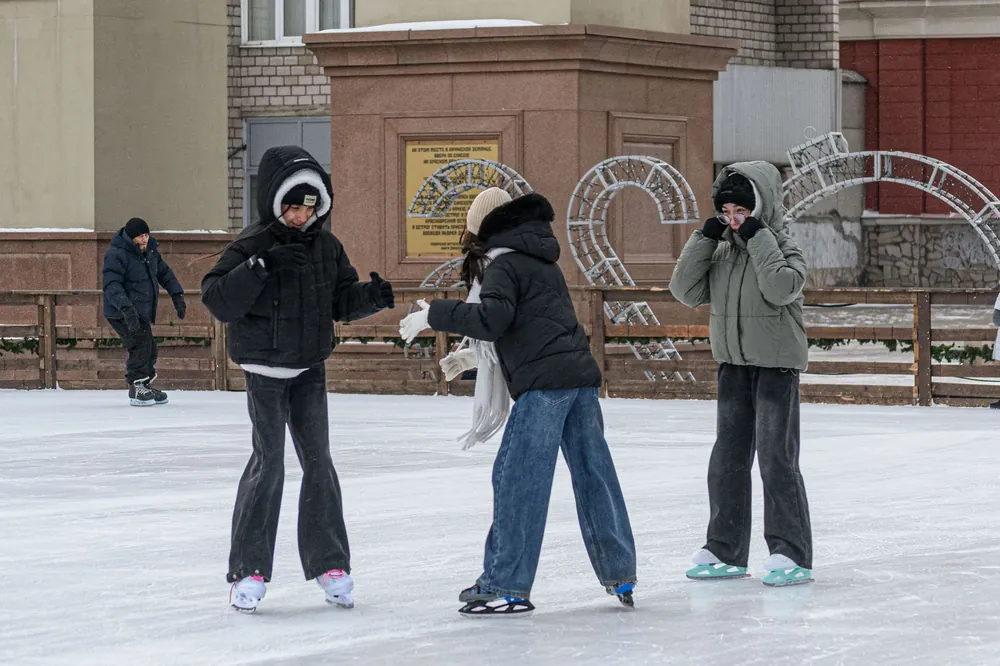 Friends ice skating on an outdoor rink in the city