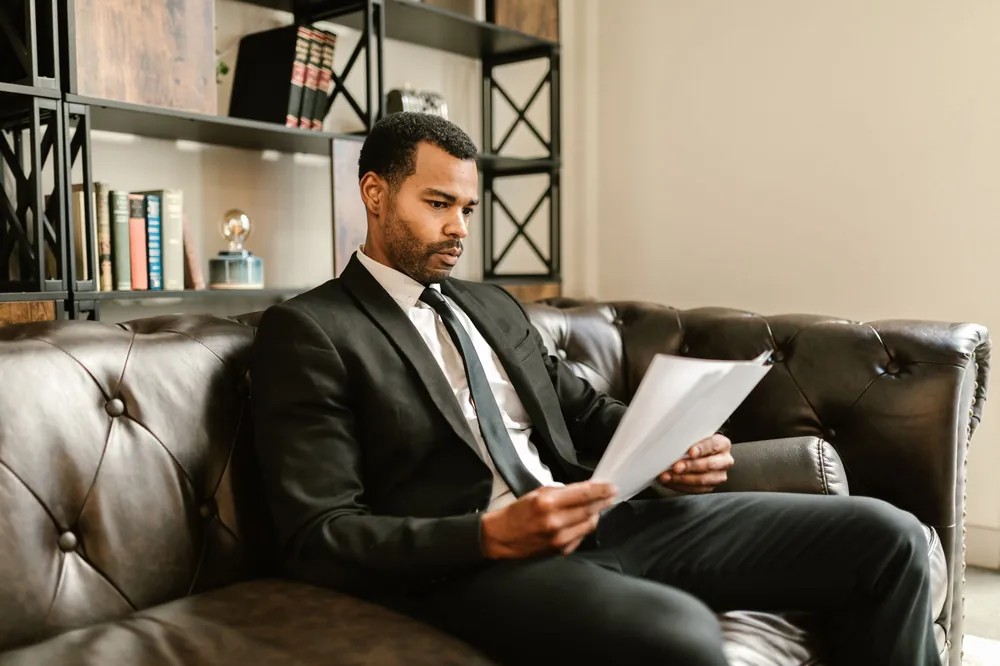 A man in a suit reading papers before signing