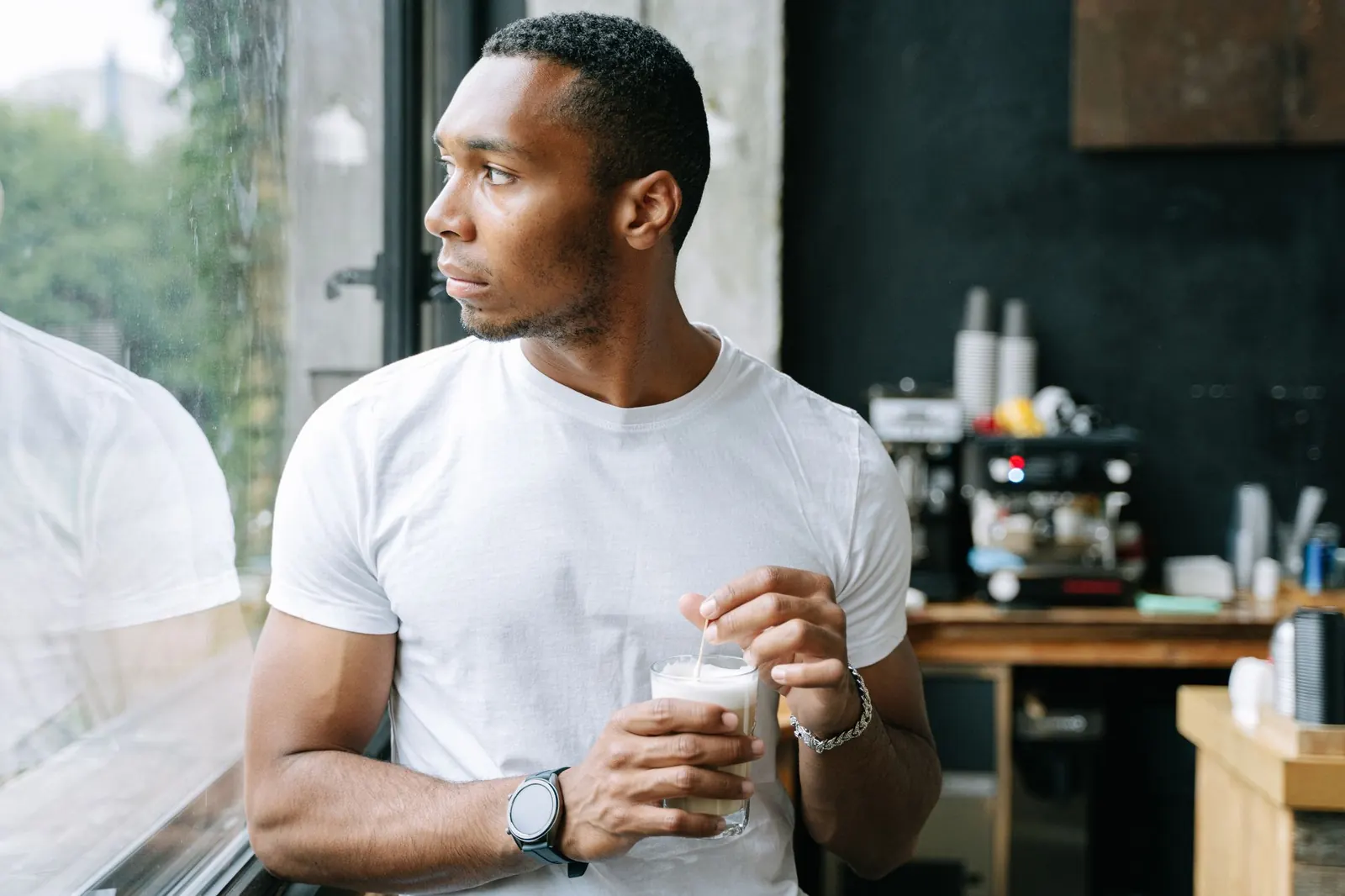 A man with a drink looking out of a café window