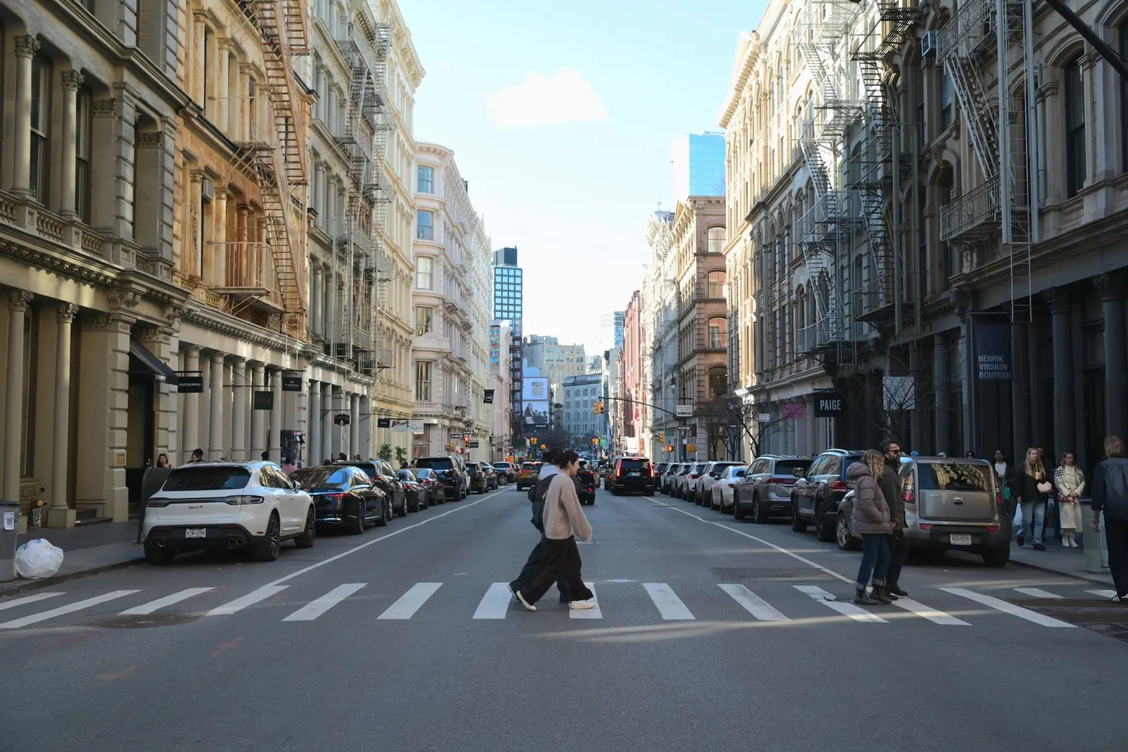 People crossing a street lined with classic buildings in SoHo