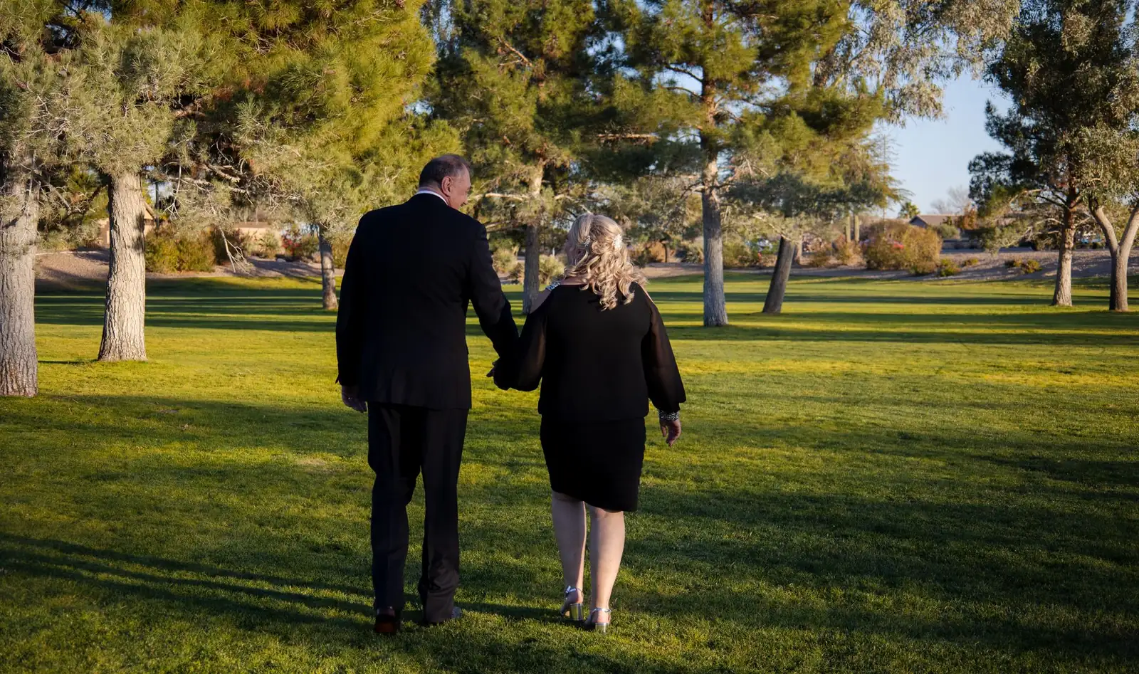 A couple walking hand in hand through a sunlit park