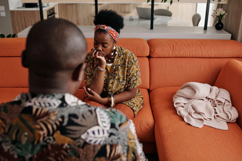 Two people having a serious conversation on a sofa
